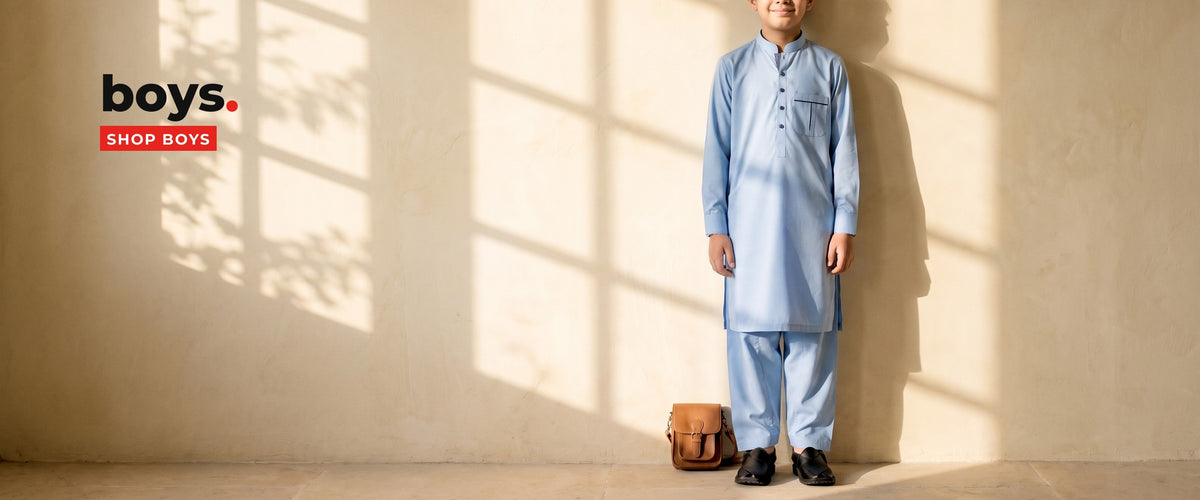 Boy in a sky blue cotton shalwar kameez against a sunlit limewash wall - Suhaib Gulzar boys' shalwar kameez